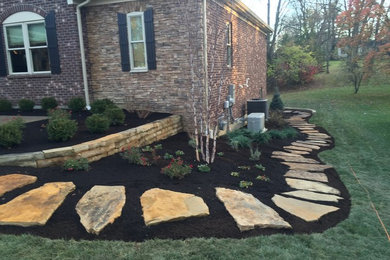 Inspiration for a mid-sized traditional backyard partial sun garden in Cincinnati with a retaining wall and natural stone pavers.