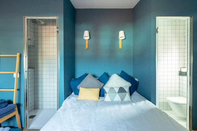 Ejemplo de dormitorio principal y blanco y madera contemporáneo de tamaño medio con paredes azules, suelo de madera en tonos medios, suelo marrón, techo inclinado y con escritorio