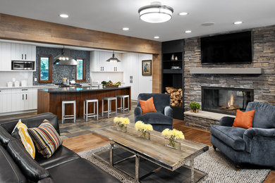 Inspiration for a medium tone wood floor living room remodel in Other with a two-sided fireplace, a stone fireplace and a wall-mounted tv