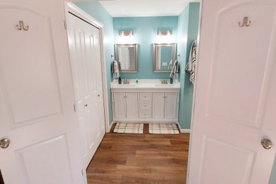 他の地域にある広いモダンスタイルのおしゃれなマスターバスルーム (白いキャビネット、バリアフリー、一体型トイレ	、白いタイル、スレートタイル、青い壁、ラミネートの床、オーバーカウンターシンク、クオーツストーンの洗面台、茶色い床、開き戸のシャワー、白い洗面カウンター、シャワーベンチ、洗面台2つ、造り付け洗面台) の写真
