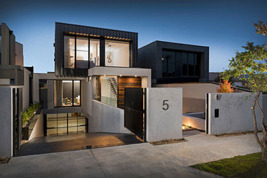 Photo of a large contemporary three-storey black house exterior in Melbourne with metal siding, a flat roof, a metal roof and a black roof.