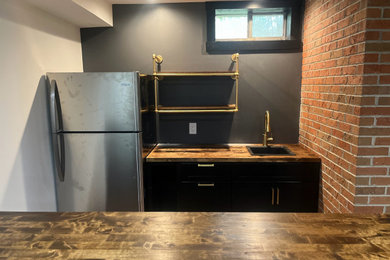 Example of a mid-sized classic single-wall light wood floor and brown floor wet bar design in Louisville with a drop-in sink, shaker cabinets, dark wood cabinets, wood countertops and brown countertops