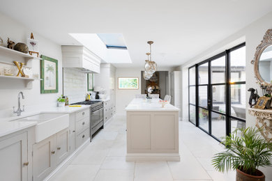This is an example of a medium sized contemporary galley kitchen/diner in Other with a belfast sink, recessed-panel cabinets, beige cabinets, granite worktops, metallic splashback, stone tiled splashback, black appliances, slate flooring, an island, white floors, white worktops and feature lighting.