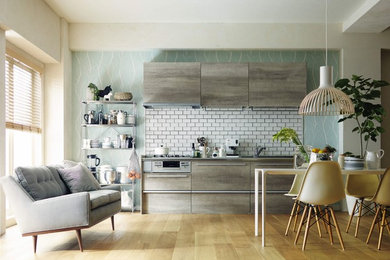 This is an example of a scandinavian kitchen in Tokyo with flat-panel cabinets, grey cabinets, white splashback, ceramic splashback, medium hardwood floors and brown floor.
