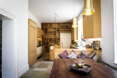 Design ideas for a large contemporary galley kitchen/diner in Other with a belfast sink, recessed-panel cabinets, light wood cabinets, wood worktops, brown splashback, wood splashback, coloured appliances, slate flooring, an island and grey floors.