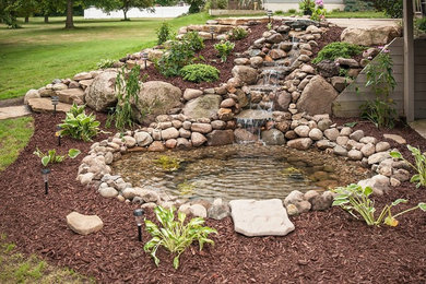 Mid-sized backyard partial sun garden in Other with with pond and natural stone pavers.
