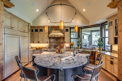 Open concept kitchen - large rustic u-shaped porcelain tile and brown floor open concept kitchen idea in Other with a farmhouse sink, recessed-panel cabinets, beige cabinets, granite countertops, brown backsplash, glass tile backsplash, paneled appliances and an island