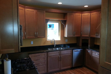 Example of a mid-sized trendy u-shaped linoleum floor enclosed kitchen design in Other with an undermount sink, shaker cabinets, light wood cabinets, granite countertops, stainless steel appliances and no island