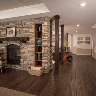 Inspiration for a large rustic walk-out basement in Detroit with grey walls, dark hardwood flooring, a two-sided fireplace and a stone fireplace surround.