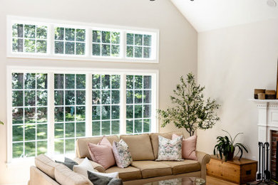 Example of a large classic open concept light wood floor and vaulted ceiling living room design in Boston with beige walls, a standard fireplace and a brick fireplace