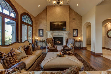Living room - large mediterranean open concept dark wood floor and brown floor living room idea in Denver with beige walls, a standard fireplace, a stone fireplace and a wall-mounted tv