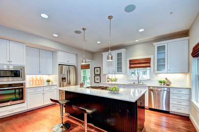 Inspiration for a mid-sized transitional l-shaped medium tone wood floor open concept kitchen remodel in DC Metro with white cabinets, white backsplash, stainless steel appliances, an island, an undermount sink, marble countertops, subway tile backsplash and shaker cabinets
