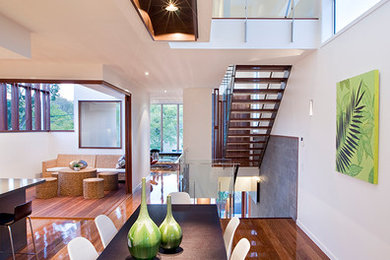 Contemporary open plan dining in Brisbane with white walls, medium hardwood floors and no fireplace.