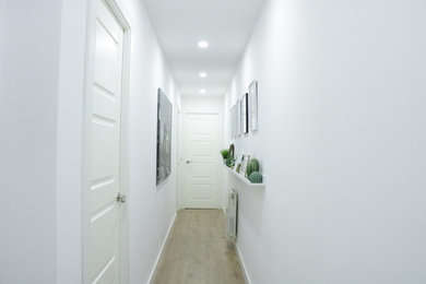 This is an example of a mid-sized modern hallway in Madrid with white walls, laminate floors and brown floor.