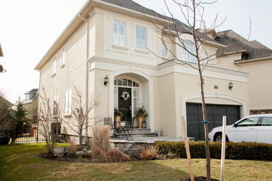 Large transitional beige two-story stucco exterior home photo in San Diego with a hip roof