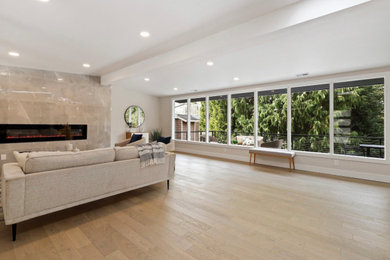 Inspiration for a large timeless light wood floor and brown floor living room remodel in Seattle with white walls, a ribbon fireplace and a stone fireplace
