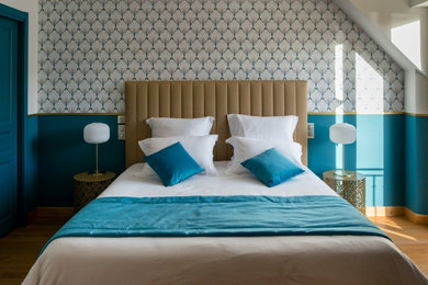 Idées déco pour une chambre contemporaine avec un mur bleu, parquet clair et du papier peint.