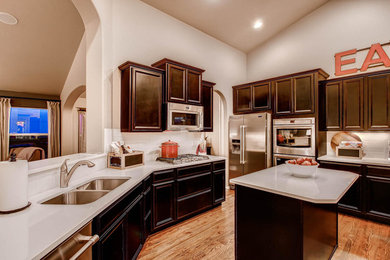 Kitchen - transitional kitchen idea in Denver with a double-bowl sink, recessed-panel cabinets, dark wood cabinets, white backsplash, subway tile backsplash, stainless steel appliances and an island