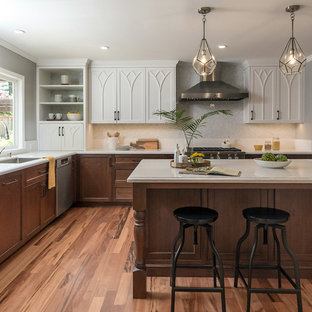 Inspiration for a large traditional u-shaped kitchen in San Francisco with an undermount sink, beaded inset cabinets, dark wood cabinets, solid surface benchtops, grey splashback, mosaic tile splashback, stainless steel appliances, light hardwood floors, with island, multi-coloured floor and white benchtop.