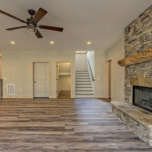 This is an example of a large traditional walk-out basement in Atlanta with beige walls, vinyl flooring, a two-sided fireplace, a stone fireplace surround and brown floors.