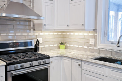 Example of a mid-sized transitional u-shaped light wood floor and brown floor enclosed kitchen design in Toronto with an undermount sink, raised-panel cabinets, white cabinets, granite countertops, beige backsplash, glass tile backsplash, stainless steel appliances, a peninsula and gray countertops