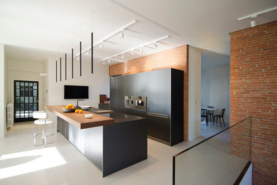 Ejemplo de cocina lineal actual de tamaño medio abierta con armarios con paneles lisos, puertas de armario negras, electrodomésticos de acero inoxidable y una isla