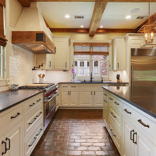 Стильный дизайн: большая п-образная кухня в стиле кантри с кладовкой, врезной раковиной, фасадами с декоративным кантом, белыми фасадами, столешницей из гранита, белым фартуком, фартуком из терракотовой плитки, техникой из нержавеющей стали, кирпичным полом и островом - последний тренд