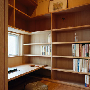 This is an example of a small modern study in Other with brown walls, light hardwood flooring and a built-in desk.