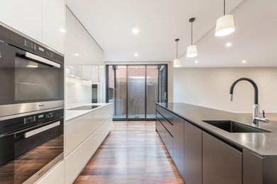 Modern eat-in kitchen in Melbourne with white cabinets, white splashback, stainless steel appliances and with island.