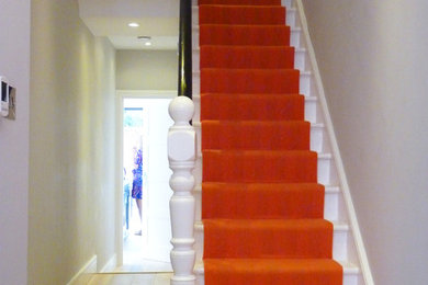 Photo of a mid-sized transitional painted wood straight staircase in London with wood risers.