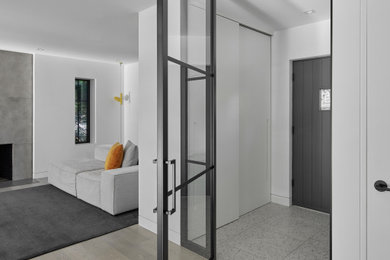 Großes Modernes Foyer mit weißer Wandfarbe, hellem Holzboden, Einzeltür, grauer Haustür und grauem Boden in Montreal
