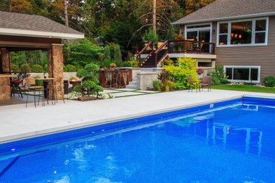 Diseño de piscina tradicional renovada grande rectangular en patio trasero con paisajismo de piscina y suelo de hormigón estampado