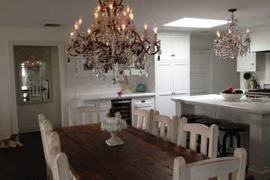 Example of a beach style dark wood floor eat-in kitchen design in Santa Barbara with an island, recessed-panel cabinets, marble countertops, gray backsplash, subway tile backsplash, paneled appliances and a farmhouse sink
