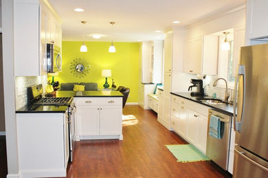 Huge trendy galley medium tone wood floor kitchen pantry photo in Chicago with an undermount sink, shaker cabinets, white cabinets, quartz countertops, gray backsplash, glass tile backsplash, white appliances and a peninsula