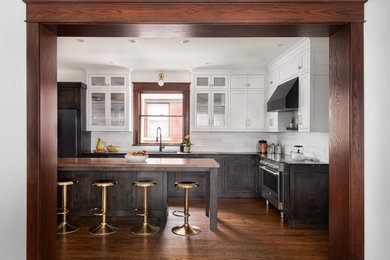 Large transitional l-shaped medium tone wood floor and brown floor open concept kitchen photo in Kansas City with an undermount sink, beaded inset cabinets, white cabinets, soapstone countertops, white backsplash, marble backsplash, black appliances, an island and black countertops