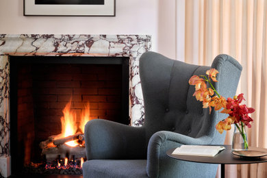 オースティンにある広いトランジショナルスタイルのおしゃれなLDK (ベージュの壁、淡色無垢フローリング、標準型暖炉、石材の暖炉まわり、ベージュの床) の写真