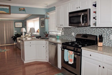 Inspiration for a mid-sized coastal galley medium tone wood floor eat-in kitchen remodel in New York with a drop-in sink, raised-panel cabinets, white cabinets, laminate countertops, blue backsplash, glass tile backsplash, stainless steel appliances and no island