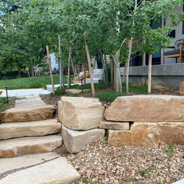 Mountain inspired minimalist boulder retaining walls and plantings.