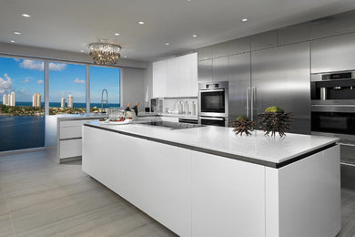 Eat-in kitchen - large modern l-shaped porcelain tile eat-in kitchen idea in Miami with an undermount sink, flat-panel cabinets, stainless steel cabinets, quartzite countertops, white backsplash, stone slab backsplash, stainless steel appliances and an island