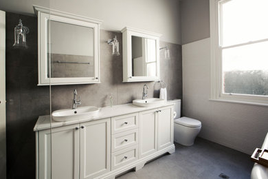 Photo of a large traditional master bathroom in Perth with furniture-like cabinets, white cabinets, a claw-foot tub, a corner shower, a two-piece toilet, white tile, ceramic tile, grey walls, ceramic floors, a vessel sink, grey floor, an open shower and white benchtops.