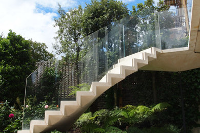 Ejemplo de escalera suspendida minimalista con escalones de piedra caliza, contrahuellas de piedra caliza y barandilla de vidrio