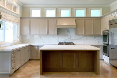 Design ideas for a large transitional u-shaped open plan kitchen in Orange County with an undermount sink, recessed-panel cabinets, grey cabinets, white splashback, porcelain splashback, stainless steel appliances, limestone floors, with island, beige floor and white benchtop.