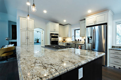 Huge elegant u-shaped porcelain tile and brown floor eat-in kitchen photo in Denver with a farmhouse sink, raised-panel cabinets, white cabinets, granite countertops, stone tile backsplash, stainless steel appliances and an island