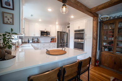 Mid-sized french country u-shaped dark wood floor, brown floor and exposed beam eat-in kitchen photo in Richmond with recessed-panel cabinets, white cabinets, quartz countertops, white backsplash, ceramic backsplash, stainless steel appliances, no island and white countertops
