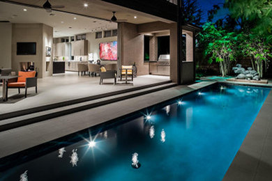 Foto de piscina alargada actual de tamaño medio rectangular en patio trasero con adoquines de hormigón