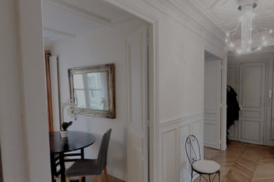 パリにある広いトラディショナルスタイルのおしゃれな玄関ロビー (白い壁、淡色無垢フローリング、茶色い床、格子天井、羽目板の壁) の写真