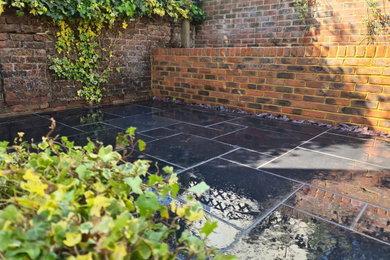 Photo of a medium sized classic back formal full sun garden for spring in Sussex with a raised bed and natural stone paving.