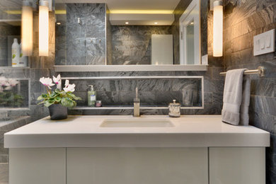 Photo of a mid-sized modern master bathroom in New York with flat-panel cabinets, white cabinets, an alcove shower, a one-piece toilet, grey walls, pebble tile floors, an undermount sink, white floor, a hinged shower door, black tile, marble and engineered quartz benchtops.