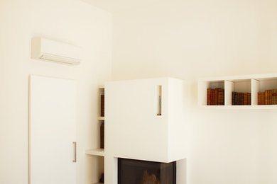 Immagine di un soggiorno contemporaneo di medie dimensioni e aperto con libreria, pareti bianche, pavimento in gres porcellanato, camino ad angolo e cornice del camino in intonaco