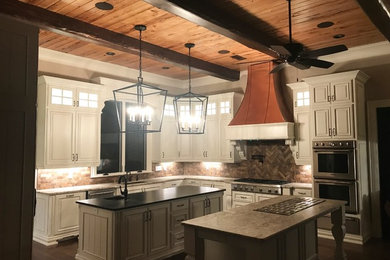 Large elegant dark wood floor kitchen photo in Jackson with an undermount sink, raised-panel cabinets, distressed cabinets, granite countertops, stainless steel appliances and two islands